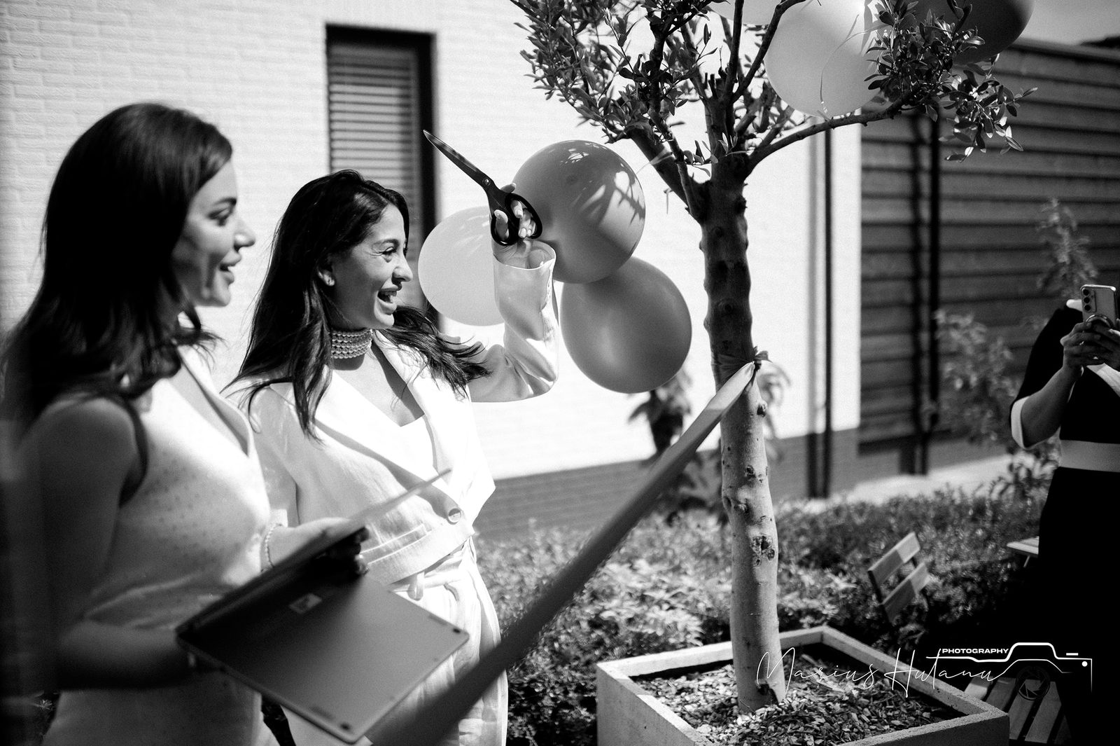 Black and white brand-event image with two women near balloons.