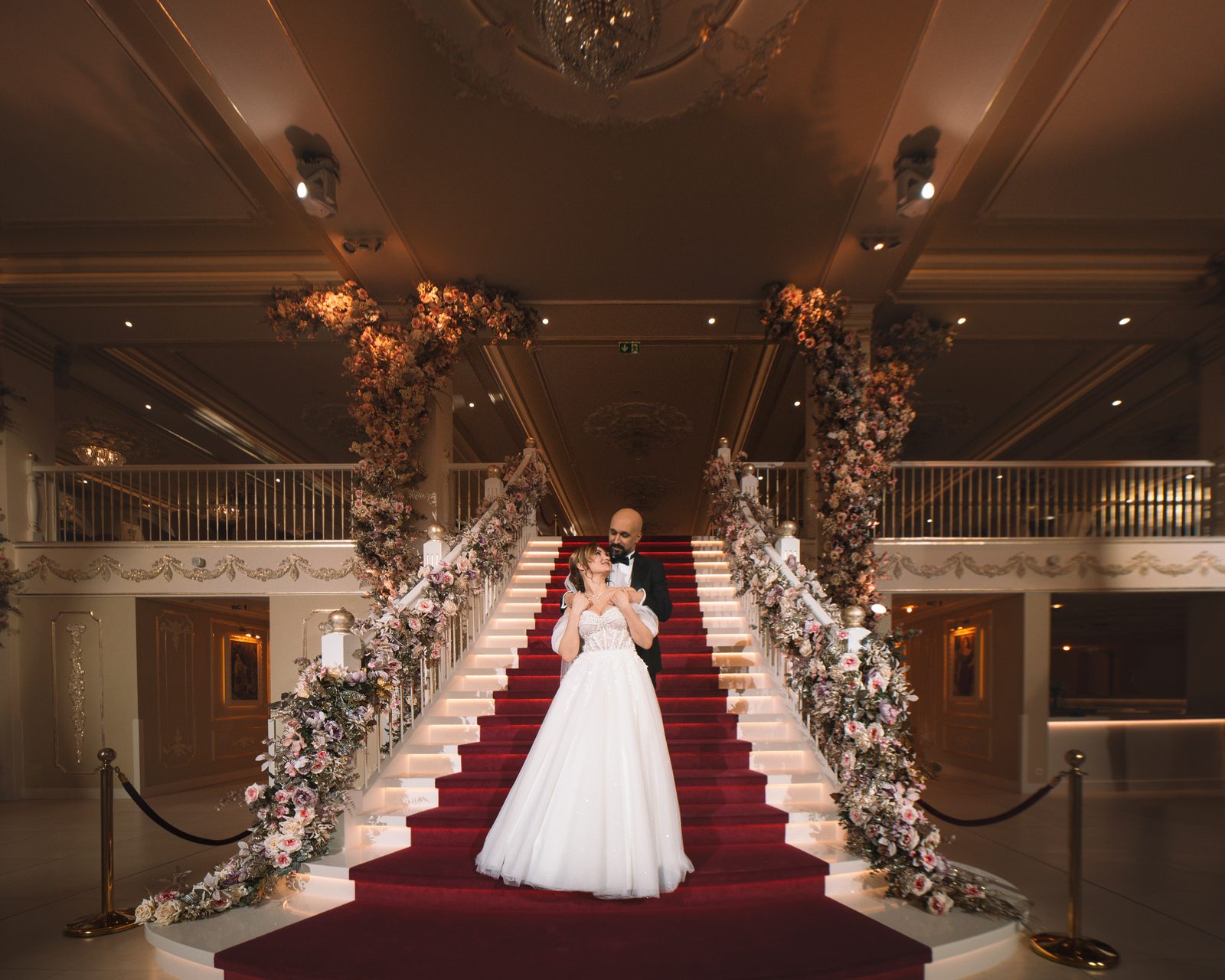 Bride and groom on a decorated staircase during a wedding.